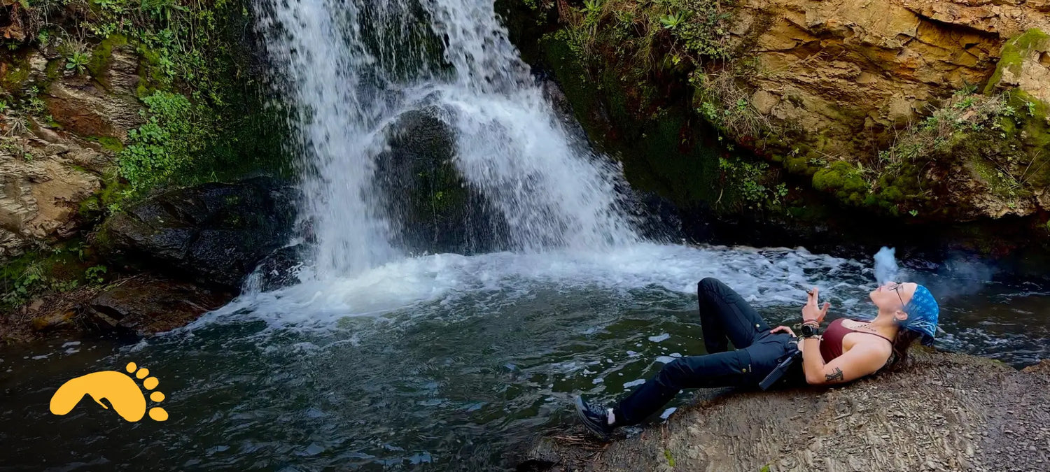 Pepper enjoying a rest after a long hike. She is sitting by a waterfall. 